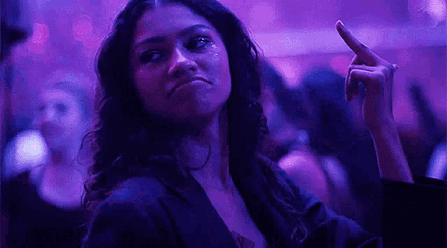 a woman is making a funny face while giving the middle finger in a club .