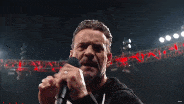 a man with a beard is standing in front of a stage with red lights .