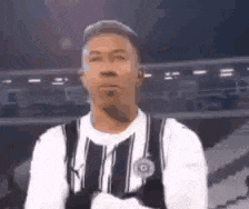 a man in a striped shirt and suspenders is standing in front of a stadium .