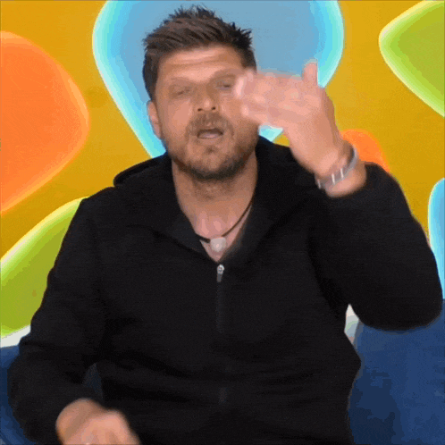 a man in a black jacket is making a gesture