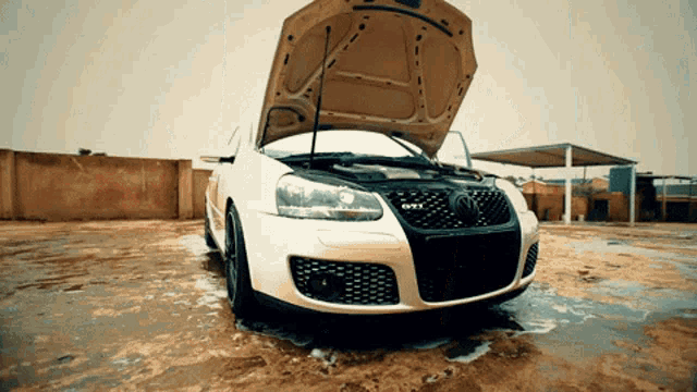 a white car with the hood up and gti written on the front