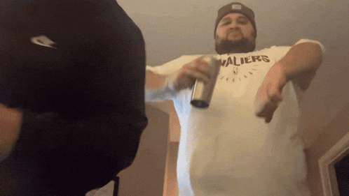 a man wearing a cleveland cavaliers shirt is holding a bottle