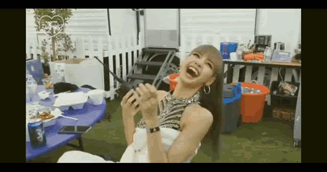a woman is laughing while sitting at a table with a microphone .
