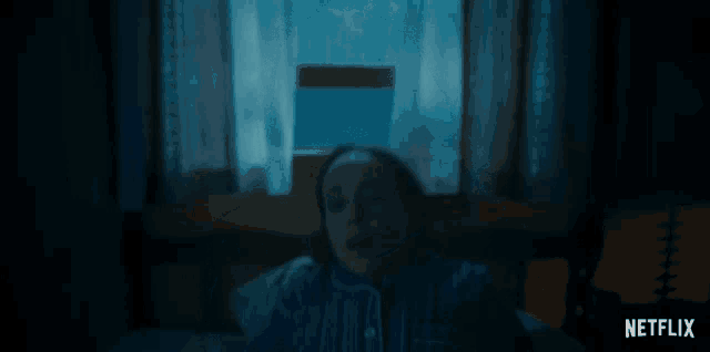 a woman is laying on a bed in a dark room with a netflix logo in the corner