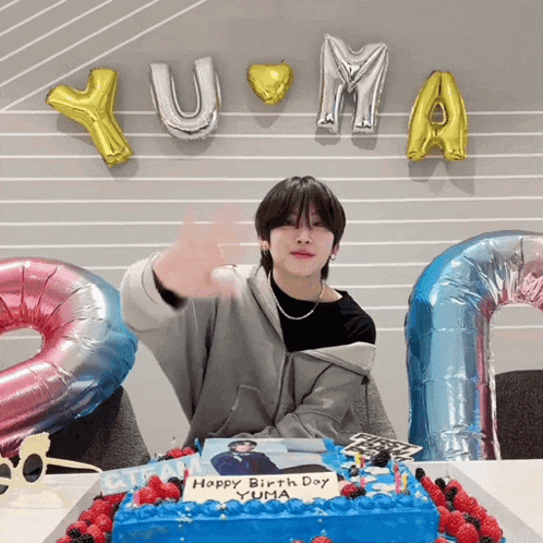 a young man is sitting in front of a birthday cake that says happy birthday yuma