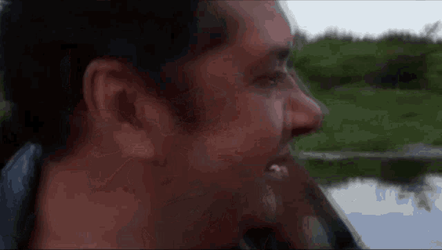 a close up of a man 's face looking out over a body of water