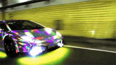 a colorful car is driving down a street in front of a wall