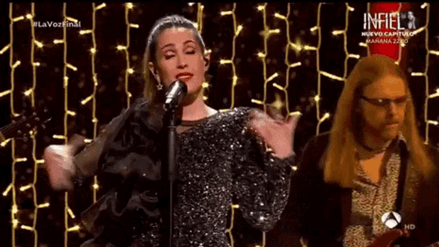 a woman is singing into a microphone while a man plays a guitar