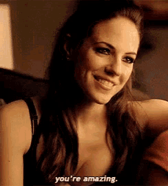 a woman in a black tank top is smiling and saying you 're amazing .