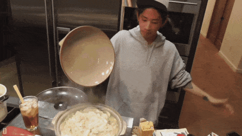 a person pouring a bowl of food into a pot of food