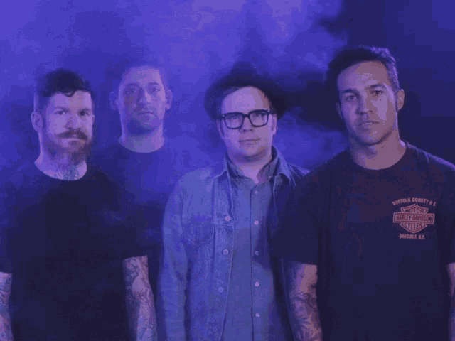 four men are posing for a picture and one of them has a harley davidson t-shirt on
