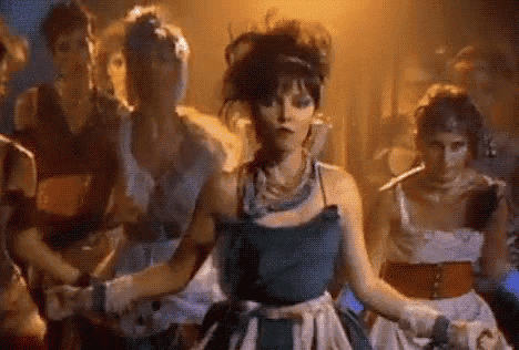 a woman in a blue dress is dancing with a group of women in white dresses .