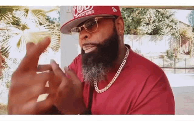 a man with a beard wearing a hat and glasses is making a funny face .