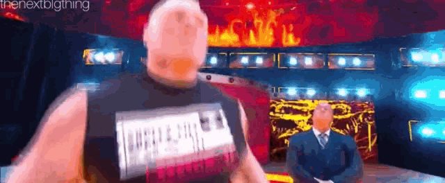 a man in a black tank top is standing in front of a fire .