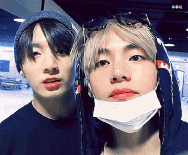 two boys wearing face masks and sunglasses pose for a picture