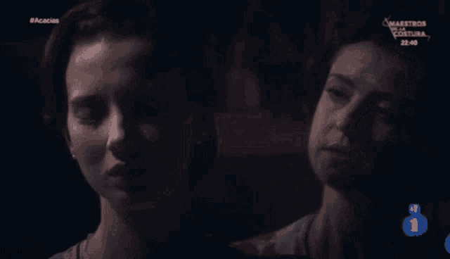 two women are looking at each other in a dark room with the number 1 on the bottom right