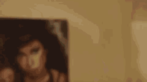 a young man with a tattoo on his face is standing in front of a painting of a woman .