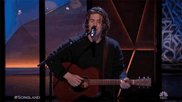 a man singing into a microphone while playing a guitar with the words songland on the bottom right