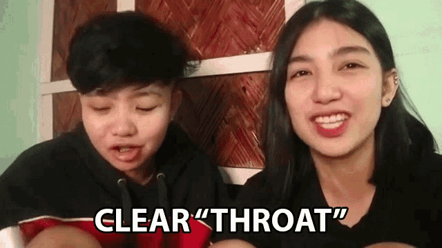 two young women are sitting next to each other and one of them is saying clear throat