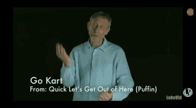 a man with a beard wearing a blue shirt is making a gesture with his hands .