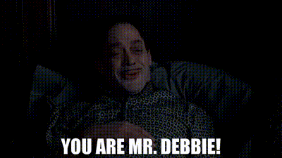 a man is laying in a bed with the words `` you are mr. debbie '' written on the screen .