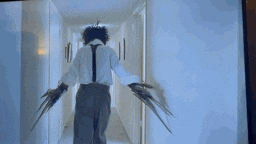 a man in a suit and tie is walking down a hallway with scissors in his hands