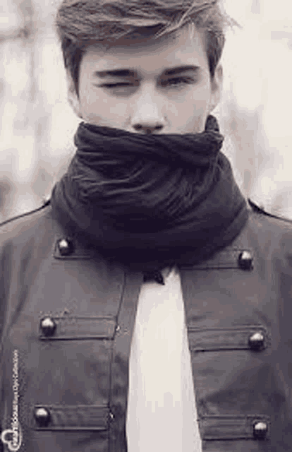 a man wearing a scarf around his neck and a jacket .