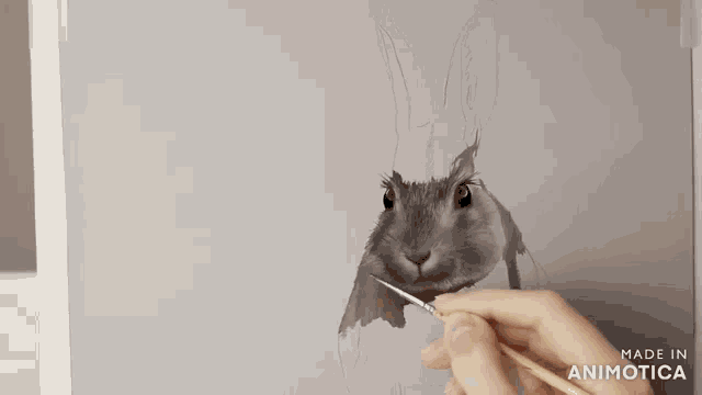 a person is painting a rabbit on a canvas with the words made in animotica visible