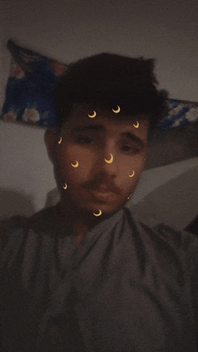 a young man with crescent moons on his face looks at the camera