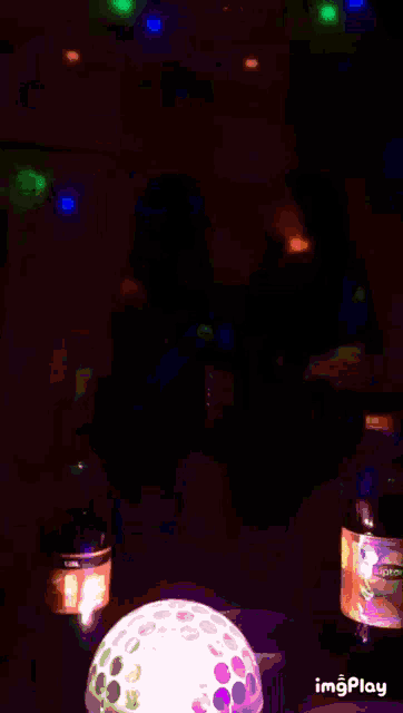 a bottle of beer sits next to a candle on a table in the dark