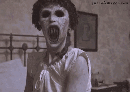 a woman with a scary face is standing in front of a bed in a bedroom .