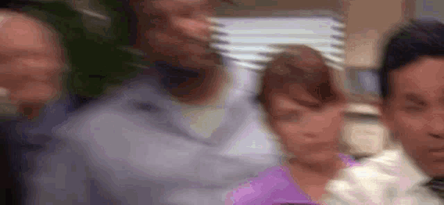 a blurry picture of a group of people standing next to each other in an office .