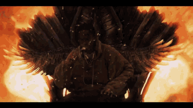 a man with wings is sitting in front of a fire background