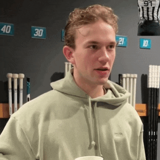 a young man wearing a green hoodie is standing in front of a wall with numbers on it