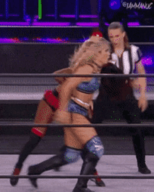 two women wrestling in a ring with a referee watching
