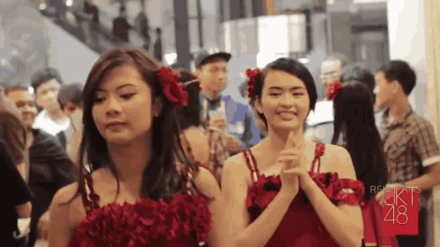 two girls wearing red dresses with roses in their hair and the number 48 on the bottom