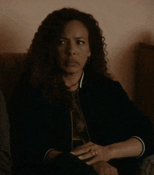 a woman with curly hair is sitting in a chair with her eyes closed and a ring on her finger .