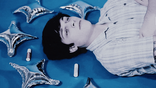 a person laying on a blue surface with silver balloons