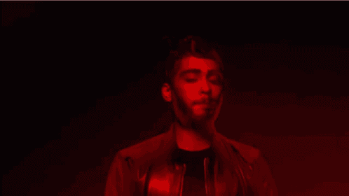 a man with a beard is singing in a red light