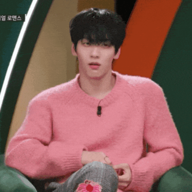 a man in a pink sweater is sitting on a chair