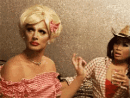 a woman in a cowboy hat is sitting next to a woman in a pink dress .