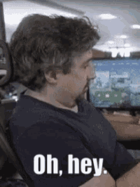 a man sitting in front of a computer with the words oh hey written on his shirt