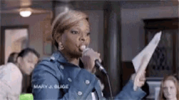 a woman is singing into a microphone while holding a piece of paper in her hand .