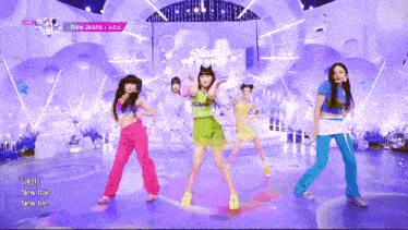 a group of girls are dancing on a stage with the words new jeans on the screen behind them