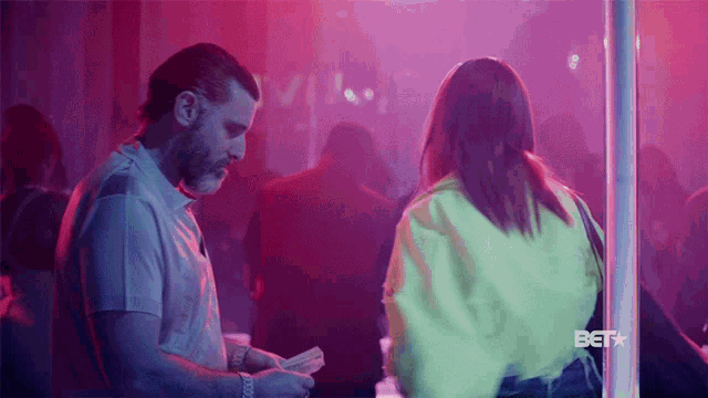 a man is counting money while a woman stands in front of a pole with the bet logo on the bottom