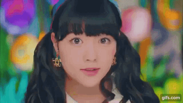 a girl with pigtails and earrings is looking at the camera .