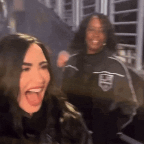 a woman is laughing and sticking her tongue out while standing next to a woman .