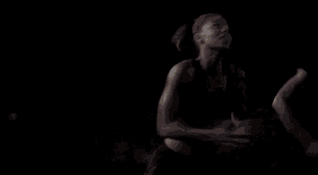a woman is standing on a basketball court at night wearing a nike sports bra .