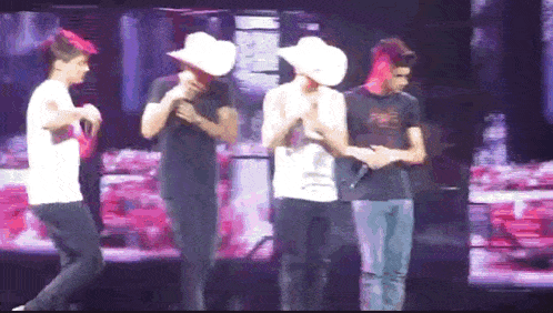 a group of men are standing on a stage wearing cowboy hats and holding microphones .