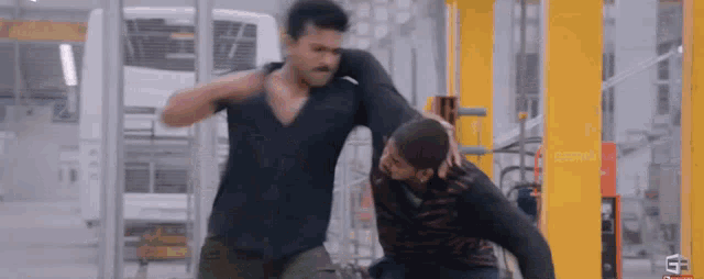 two men are fighting in a room with a yellow pole .